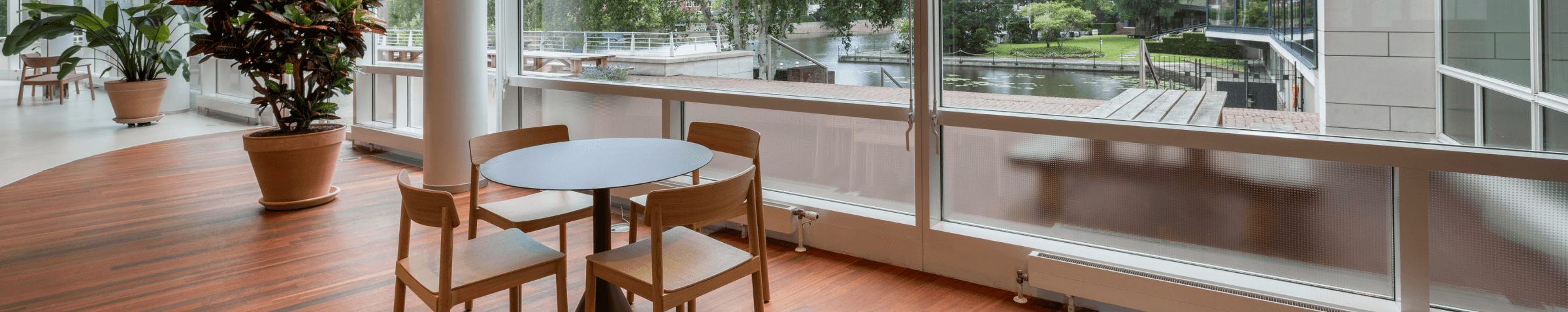 Small round table with wooden chairs next to large window overlooking water HVK Stevens