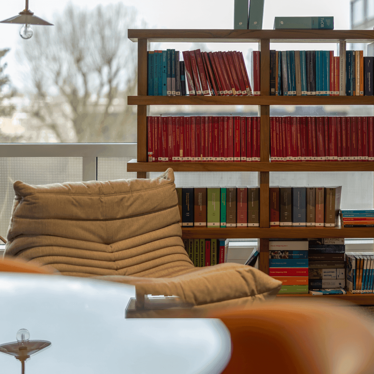 Boekenkast met gekleurde boeken naast comfortabele stoel