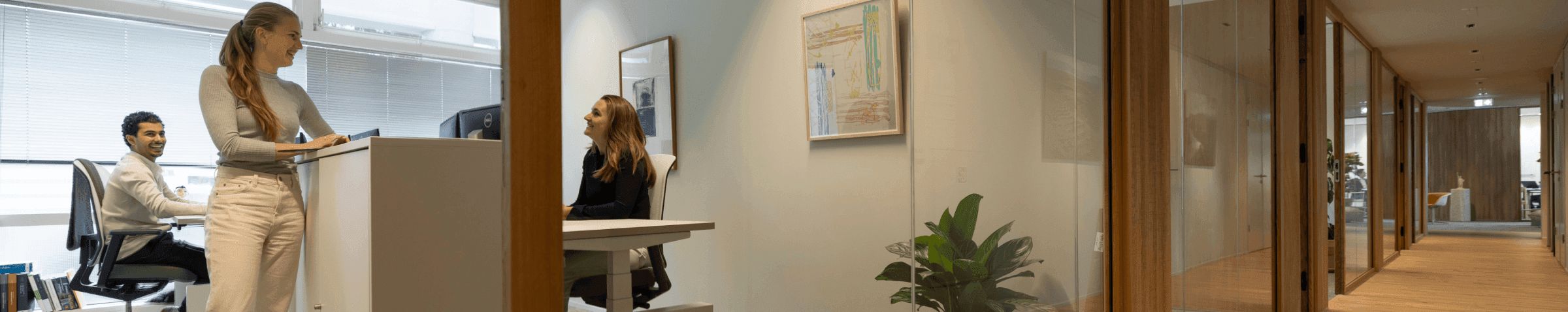 Drie collega’s lachend en overleggend in lichte kantoorruimte