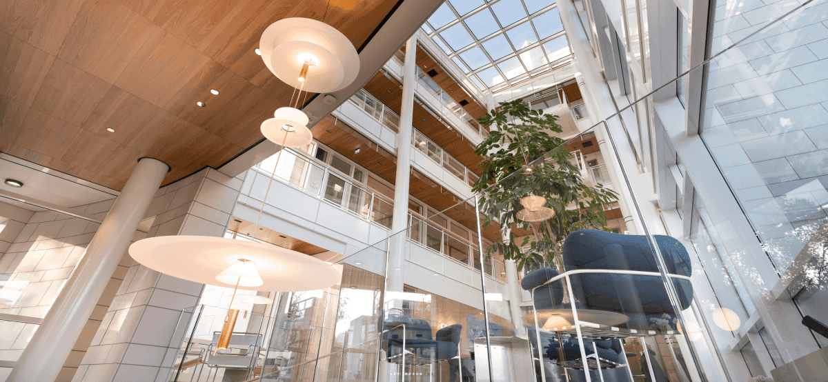 Glazen atrium met grote plant en blauwe stoelen