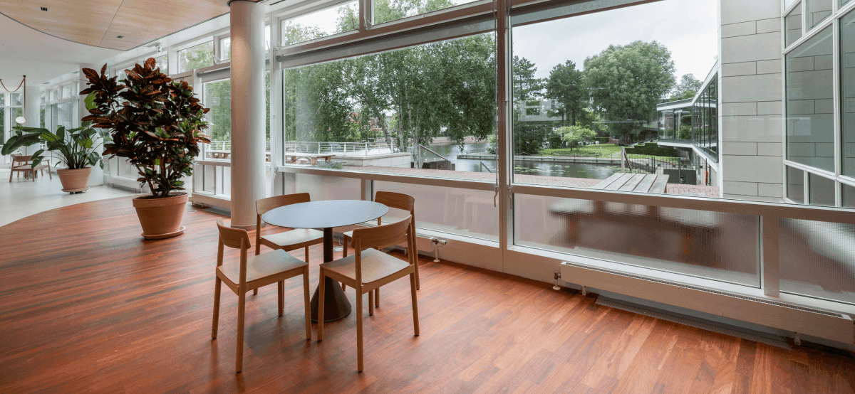 Kleine ronde tafel met houten stoelen naast groot raam met uitzicht op water