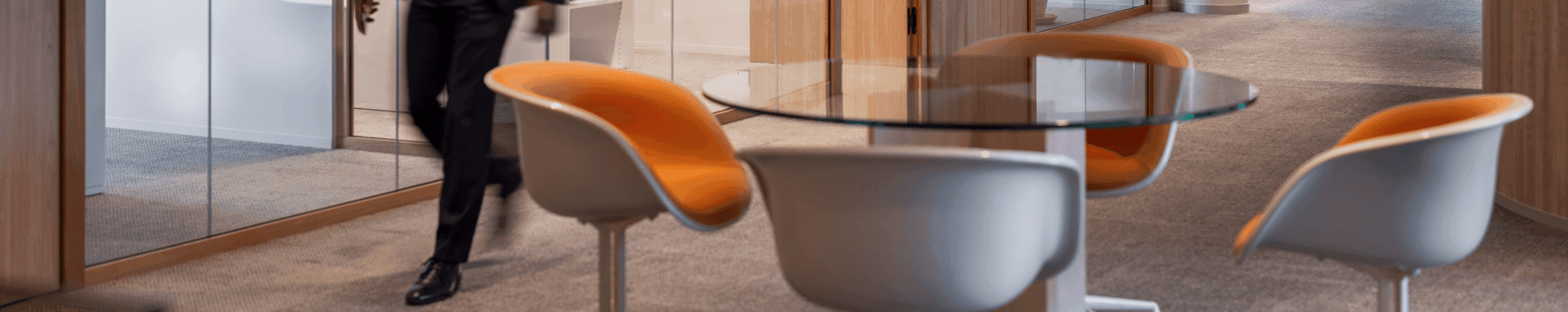 Man in suit walking past meeting rooms with glass walls