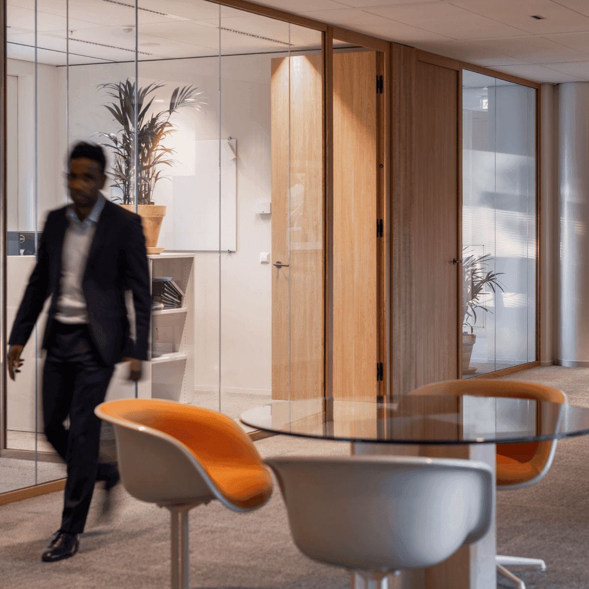 Man in suit walking past meeting rooms with glass walls