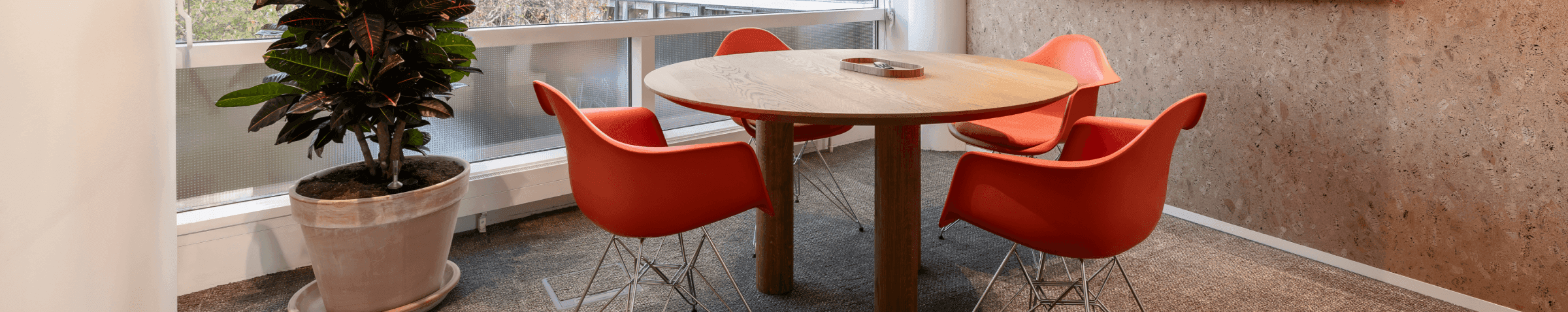 Ronde houten tafel met oranje stoelen in vergaderruimte