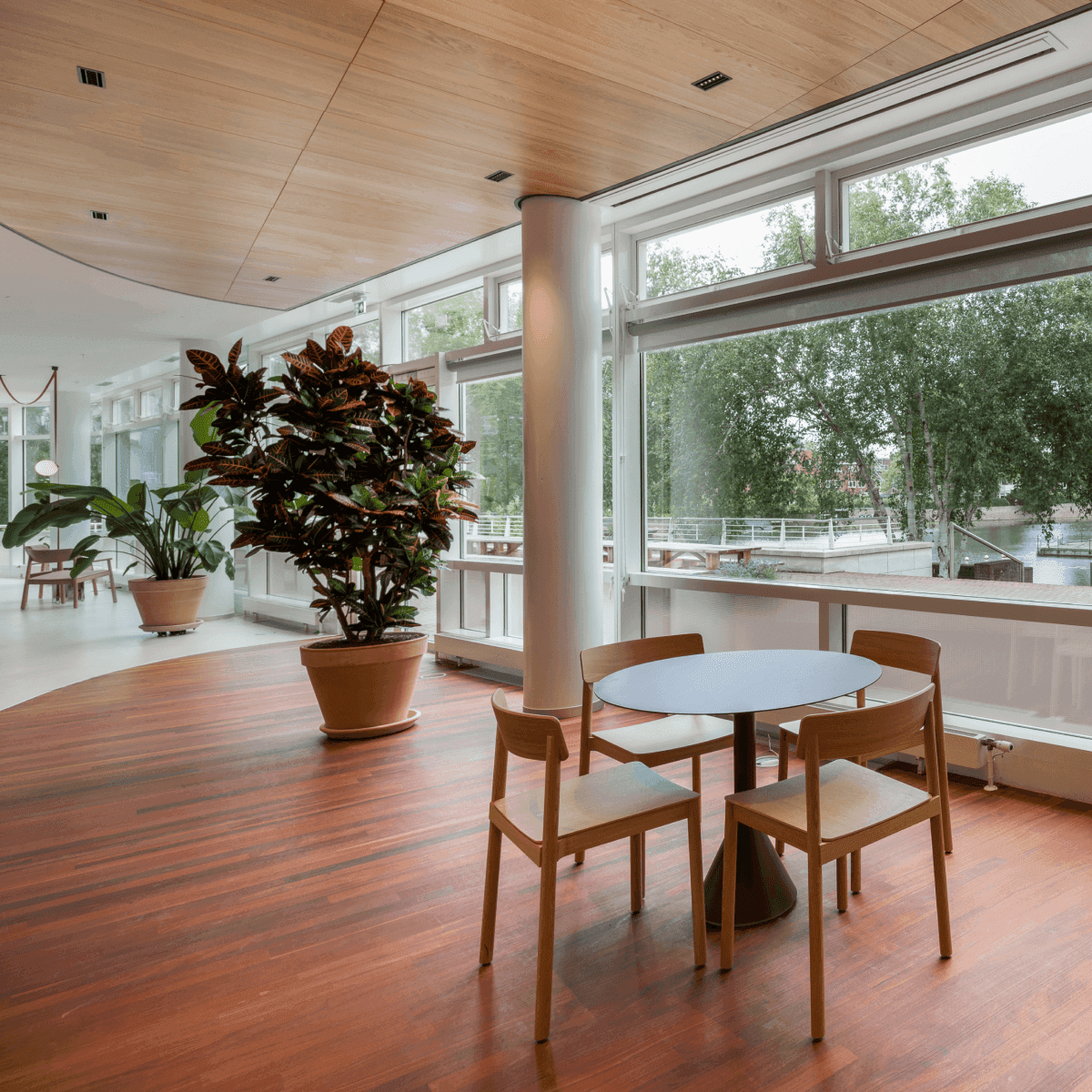 Small round table with wooden chairs next to large window overlooking water