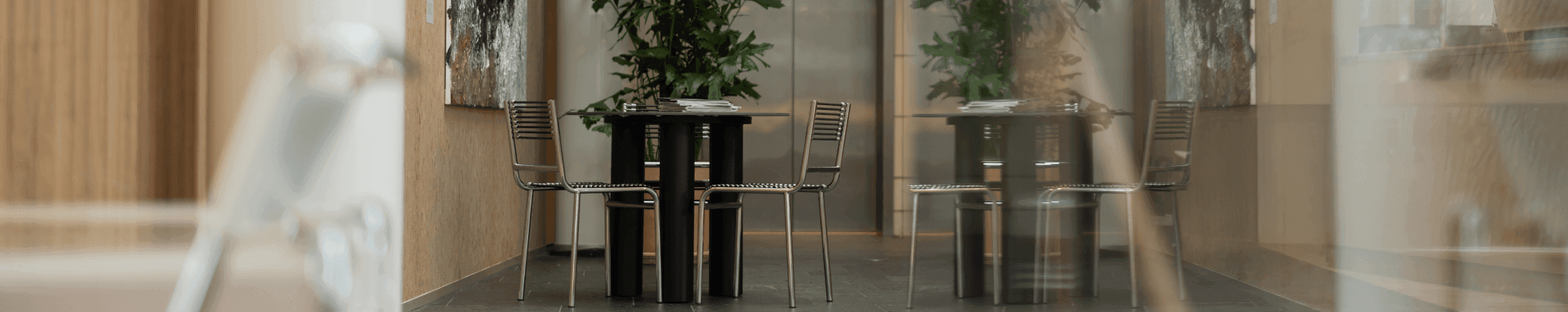 Tafel met metalen stoelen naast planten en kunstwerk