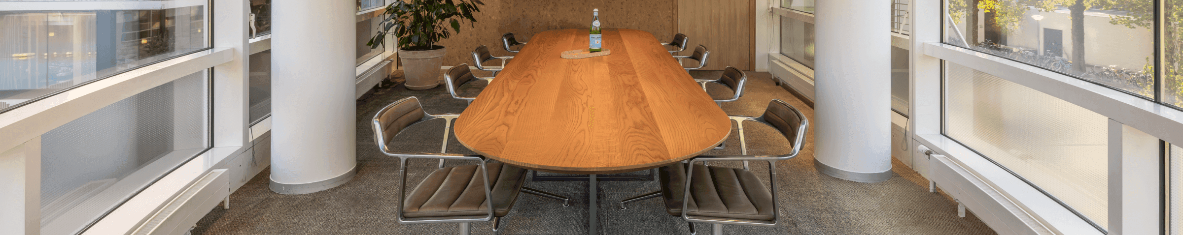 Vergaderruimte met houten tafel en plant