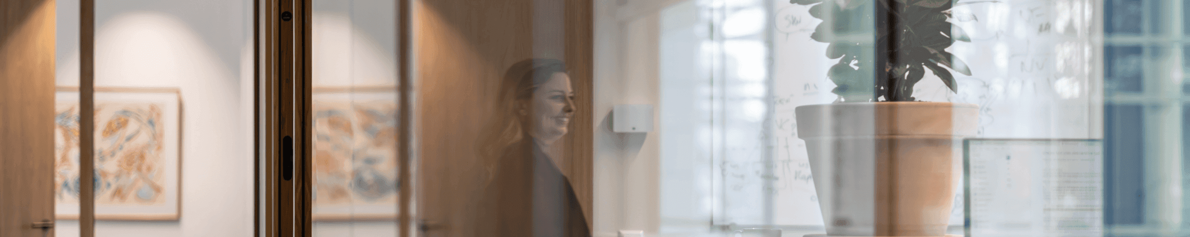 Vrouw zichtbaar via reflectie naast whiteboard en plant