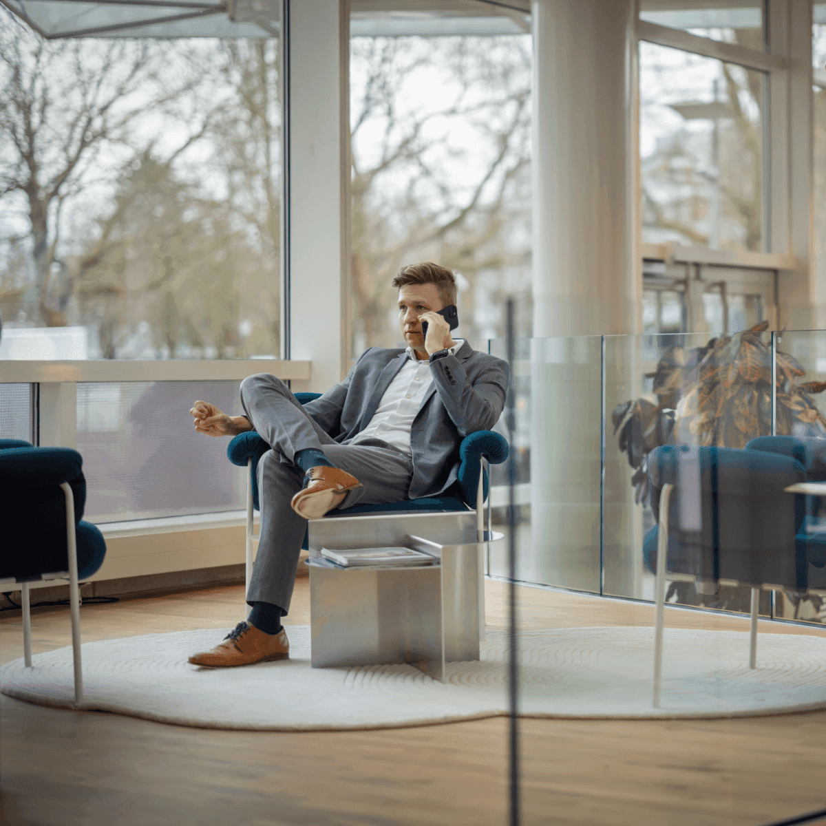 Zakenman in grijs pak telefonerend in loungehoek